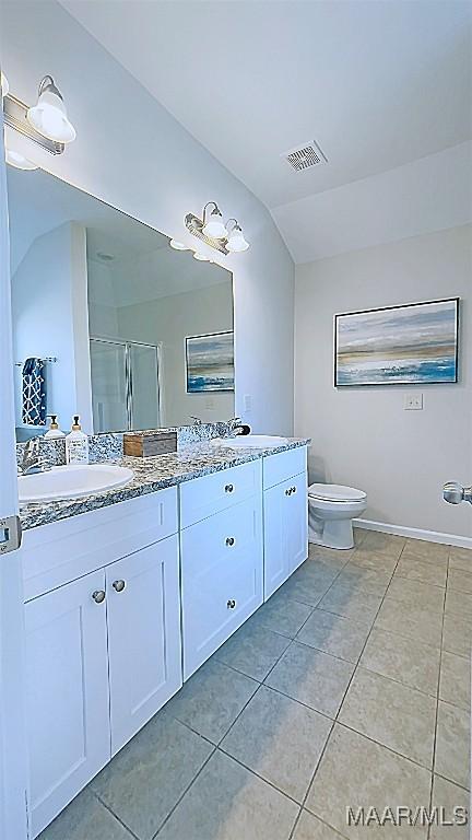 bathroom featuring visible vents, a shower stall, lofted ceiling, double vanity, and a sink