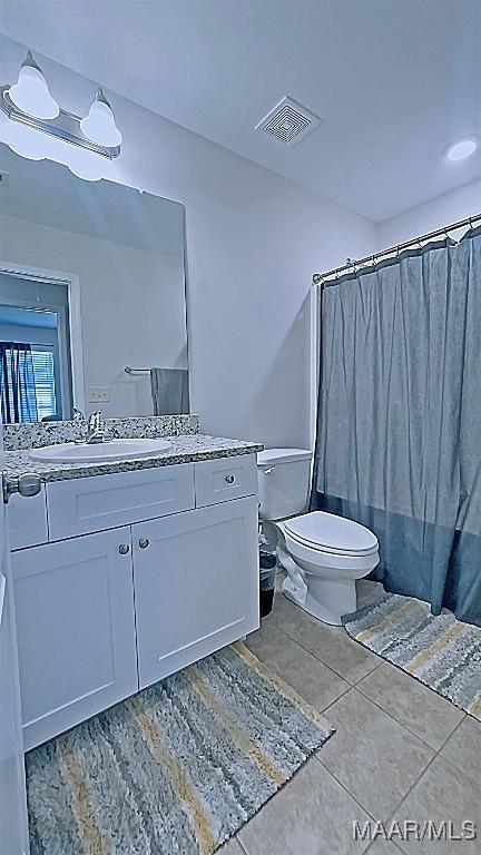 full bath with vanity, a shower with curtain, visible vents, tile patterned flooring, and toilet