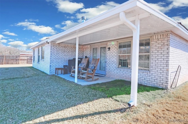 exterior space with a patio, fence, brick siding, and a lawn