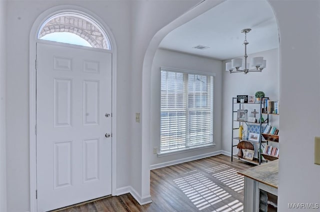 foyer entrance with arched walkways, a notable chandelier, and plenty of natural light