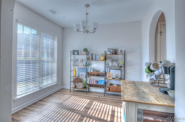 dining area featuring a chandelier, plenty of natural light, arched walkways, and wood finished floors