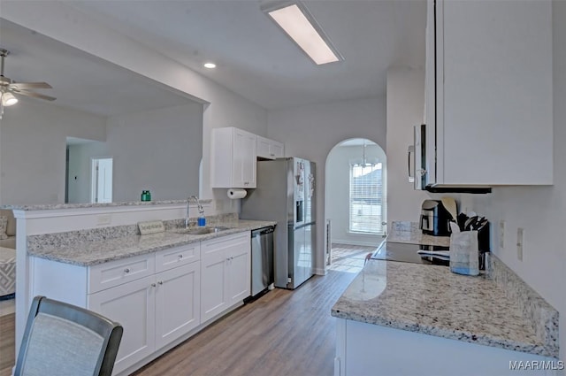 kitchen with a sink, stainless steel appliances, a peninsula, and white cabinetry