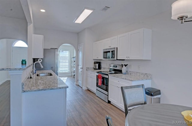 kitchen featuring a sink, light wood-style floors, appliances with stainless steel finishes, and white cabinets