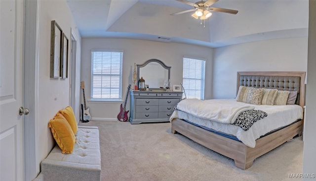 bedroom featuring multiple windows, carpet, a raised ceiling, and a ceiling fan