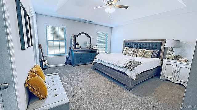 carpeted bedroom with ceiling fan and a tray ceiling