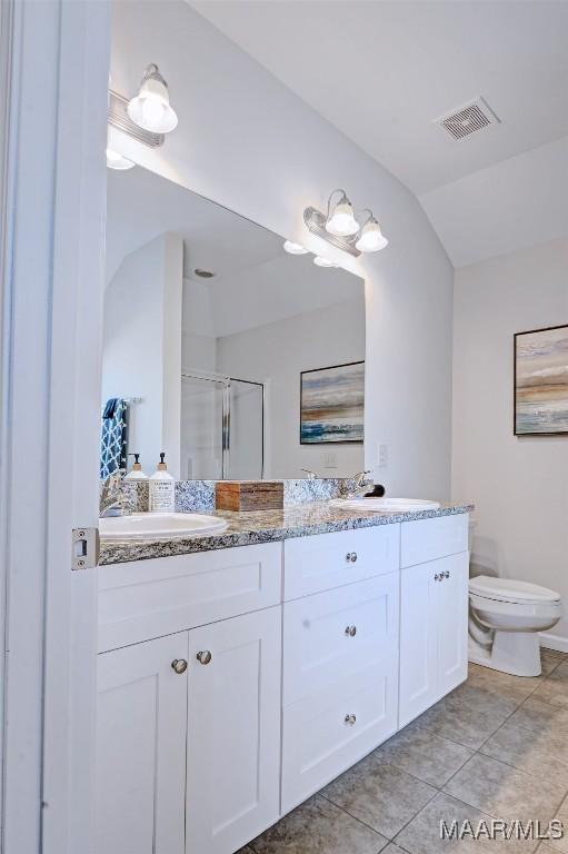 bathroom featuring visible vents, toilet, a stall shower, a sink, and double vanity