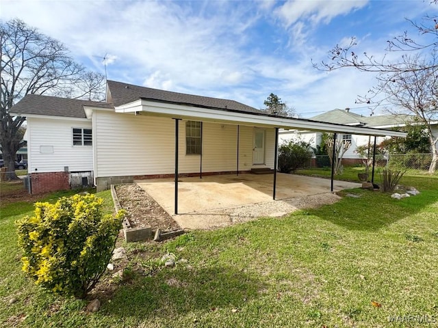 back of house featuring a shingled roof, fence, a lawn, a carport, and a patio