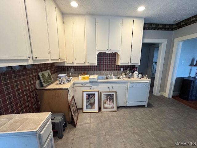 kitchen featuring dishwasher, white cabinets, tasteful backsplash, and a sink