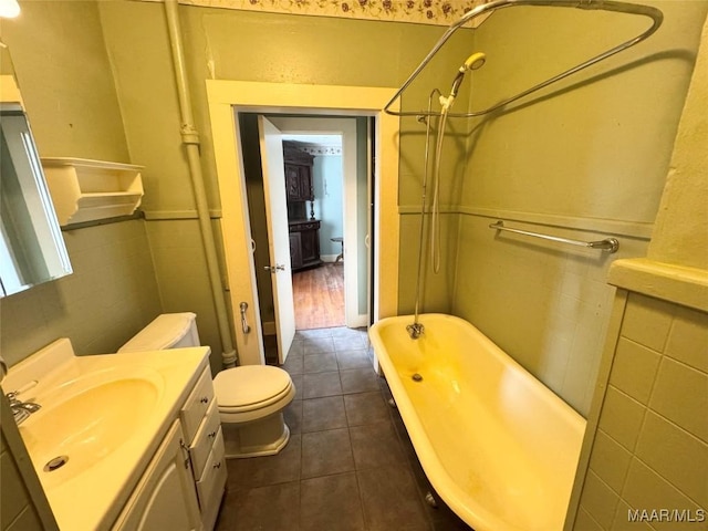 bathroom featuring a wainscoted wall, toilet, tile walls, tile patterned flooring, and vanity