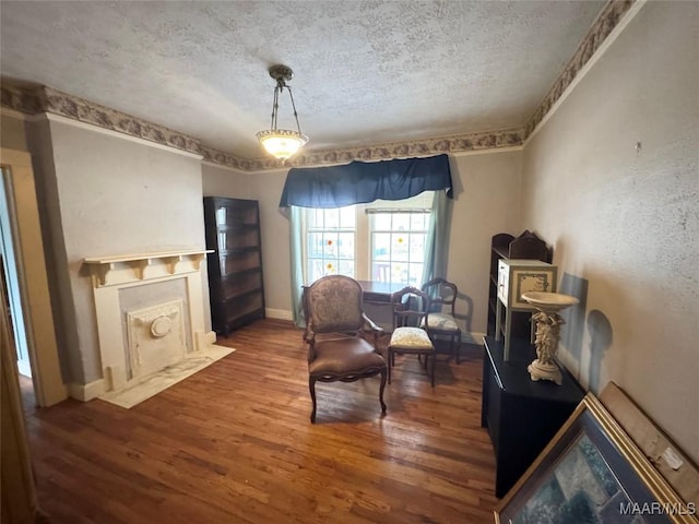 sitting room featuring a fireplace with flush hearth, wood finished floors, baseboards, and a textured ceiling