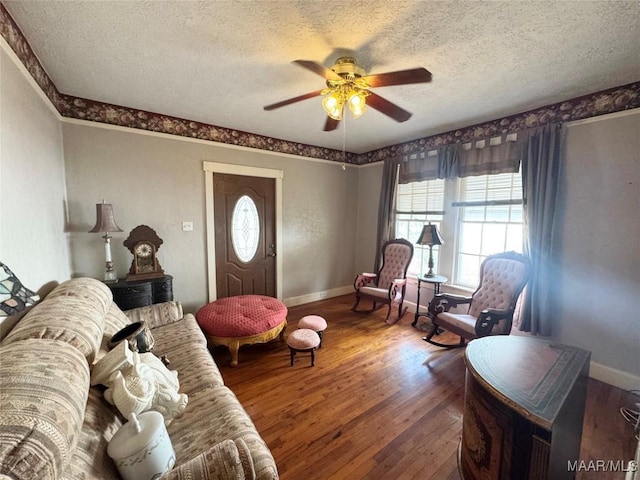 living area with baseboards, a textured ceiling, ceiling fan, and hardwood / wood-style flooring