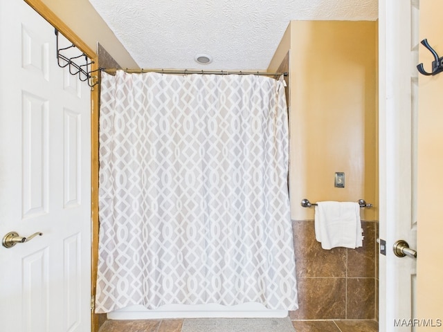 full bath with a shower with shower curtain, a textured ceiling, and tile walls