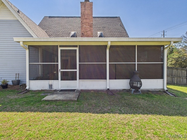 back of house with a lawn, a chimney, a sunroom, and fence