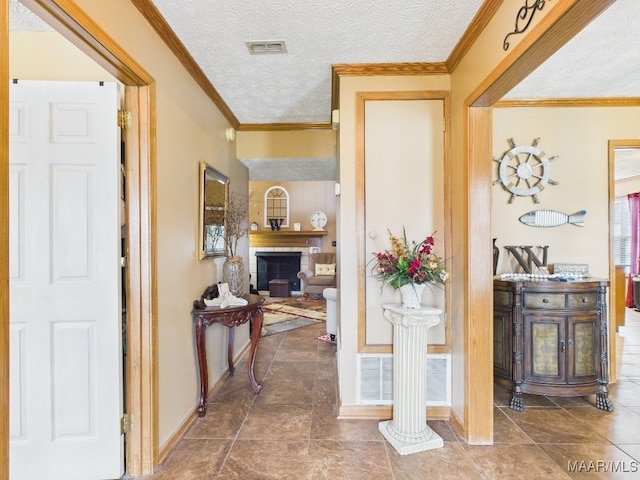 hall with visible vents, a textured ceiling, crown molding, and baseboards