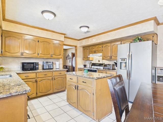 kitchen with ornamental molding, under cabinet range hood, black microwave, stainless steel fridge, and a center island