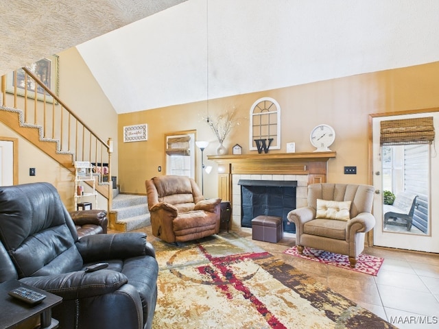 living room with a tiled fireplace, stairway, tile patterned flooring, and high vaulted ceiling