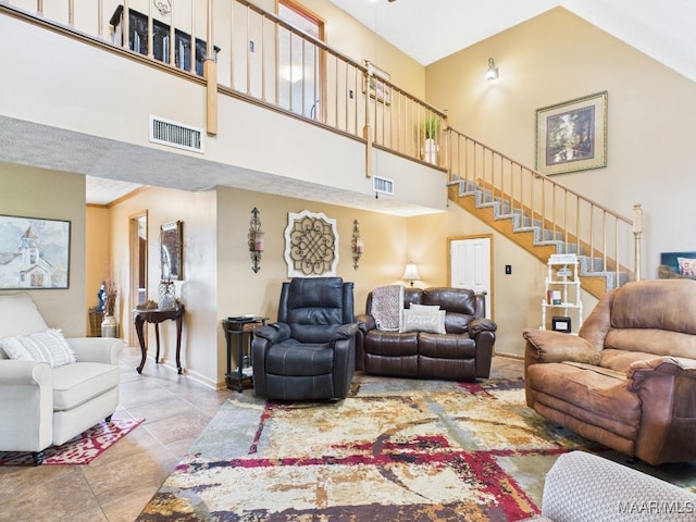 tiled living area with a high ceiling, stairway, and visible vents