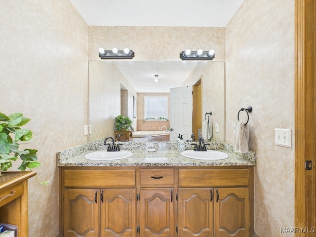 full bath featuring a sink, a tub, and double vanity