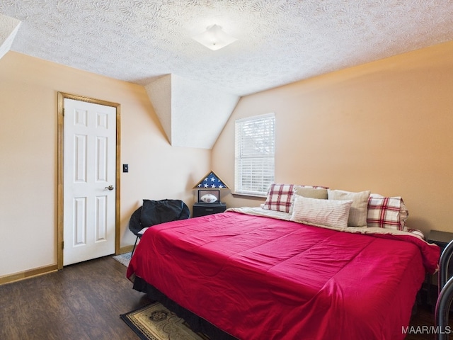 bedroom with baseboards, a textured ceiling, lofted ceiling, and wood finished floors