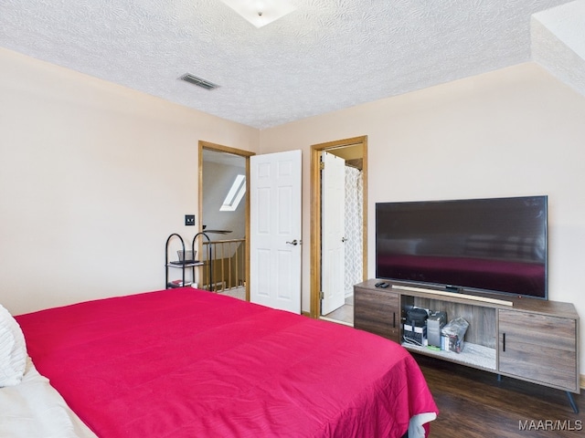 bedroom with visible vents, a textured ceiling, and wood finished floors