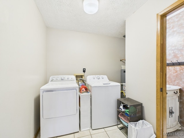 washroom featuring a textured ceiling, laundry area, light tile patterned flooring, and washing machine and clothes dryer