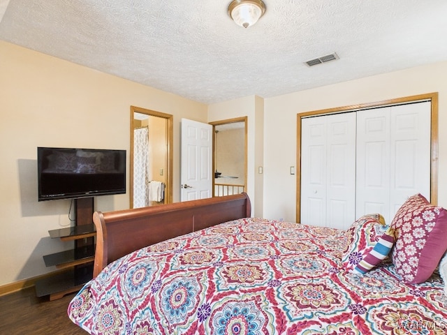 bedroom featuring visible vents, a textured ceiling, wood finished floors, a closet, and baseboards