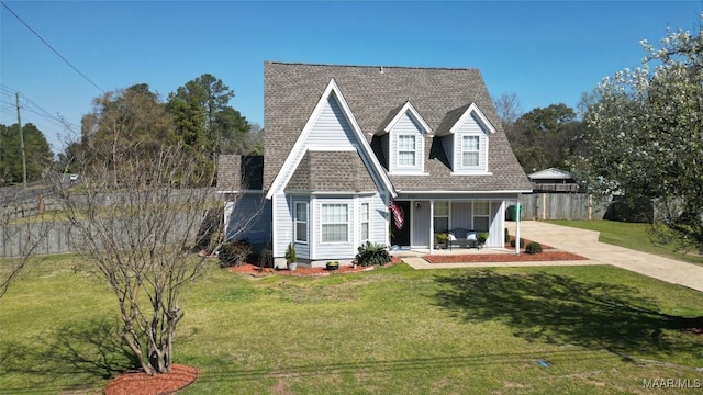 view of front of house featuring fence, concrete driveway, a front lawn, and a shingled roof