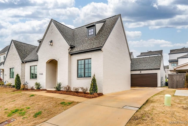 view of front of property with brick siding, concrete driveway, and a shingled roof