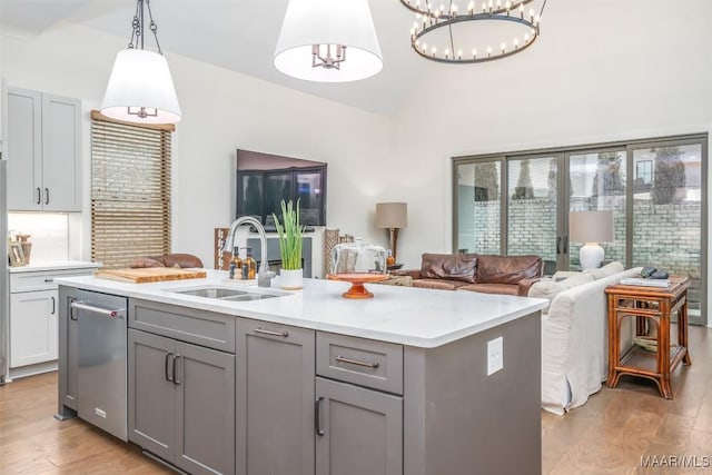 kitchen with lofted ceiling, light wood-type flooring, gray cabinets, and a sink