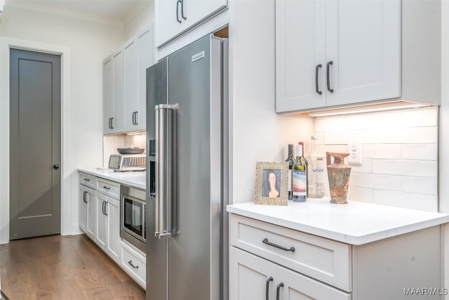 kitchen with stainless steel appliances, tasteful backsplash, wood finished floors, and light countertops