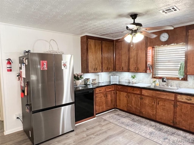 kitchen with light wood-type flooring, visible vents, brown cabinets, a ceiling fan, and freestanding refrigerator