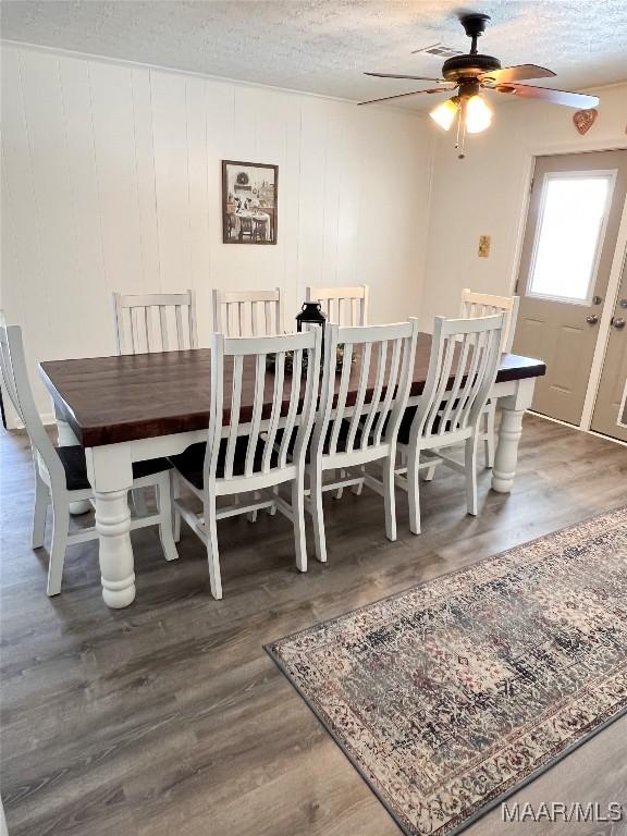 dining space featuring visible vents, a textured ceiling, wood finished floors, and a ceiling fan