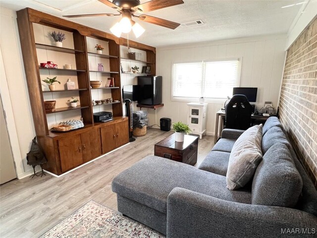 living room featuring visible vents, ceiling fan, a textured ceiling, and light wood-style floors