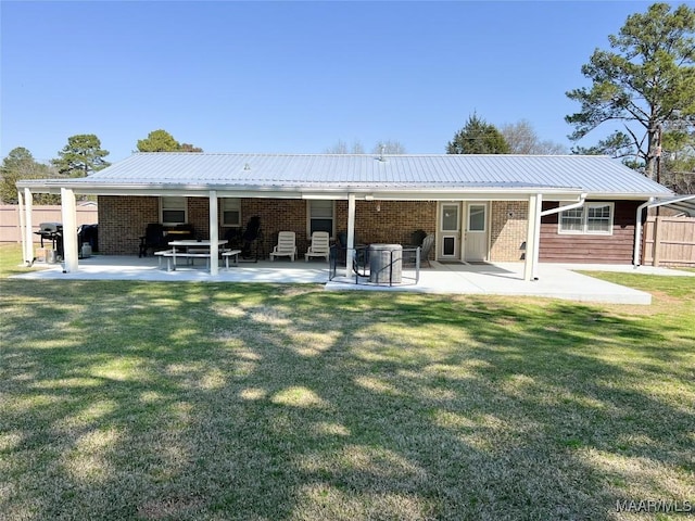 rear view of house with a patio, metal roof, a yard, and fence