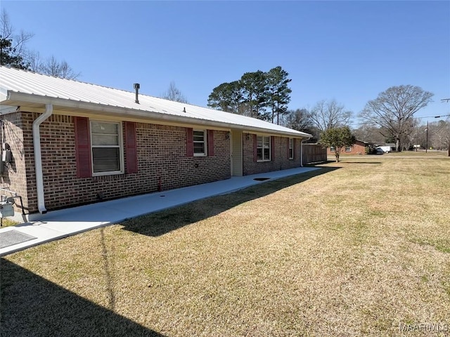 view of side of property featuring brick siding, metal roof, and a yard