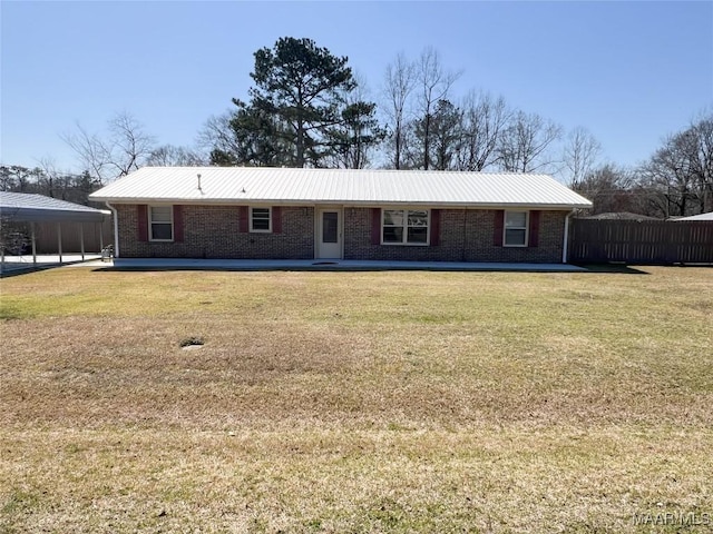 view of front of property featuring brick siding, metal roof, a front lawn, and fence