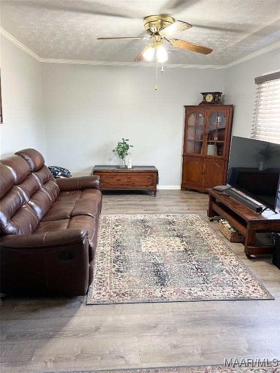 living room featuring wood finished floors, a ceiling fan, and ornamental molding