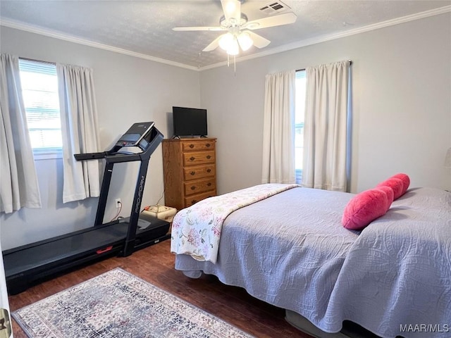 bedroom featuring visible vents, ornamental molding, a ceiling fan, and wood finished floors