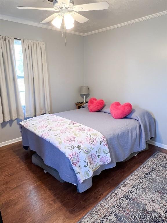 bedroom featuring a ceiling fan, wood finished floors, baseboards, and ornamental molding