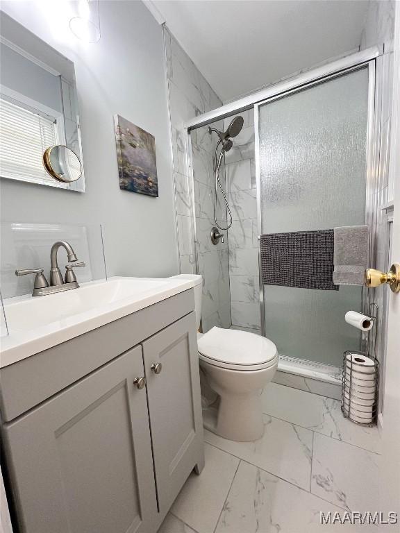 full bath with a marble finish shower, toilet, marble finish floor, and vanity