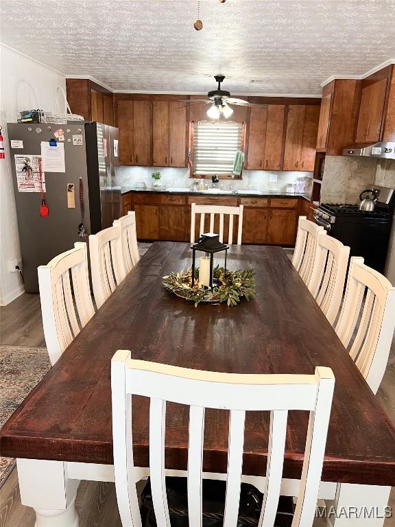 dining area with wood finished floors, a textured ceiling, and ceiling fan