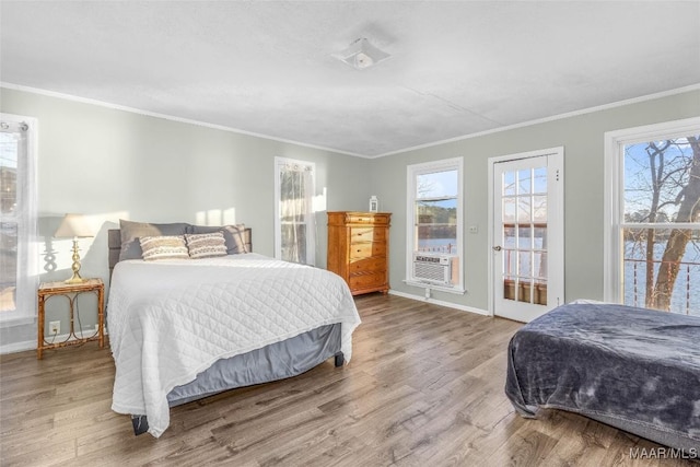 bedroom with cooling unit, wood finished floors, baseboards, and ornamental molding