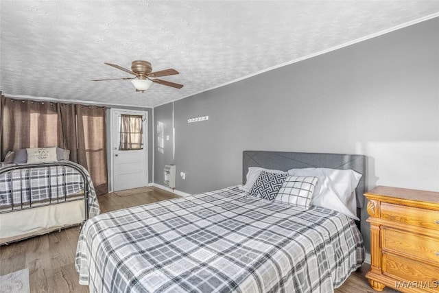 bedroom featuring ceiling fan, a textured ceiling, wood finished floors, and ornamental molding