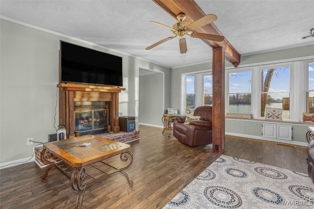 living room with wood finished floors, baseboards, a fireplace, ceiling fan, and crown molding