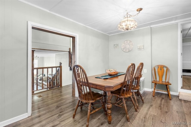 dining space featuring wood finished floors, visible vents, baseboards, ornamental molding, and a notable chandelier