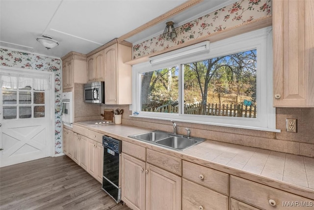 kitchen with light brown cabinetry, stainless steel microwave, dishwasher, and a sink