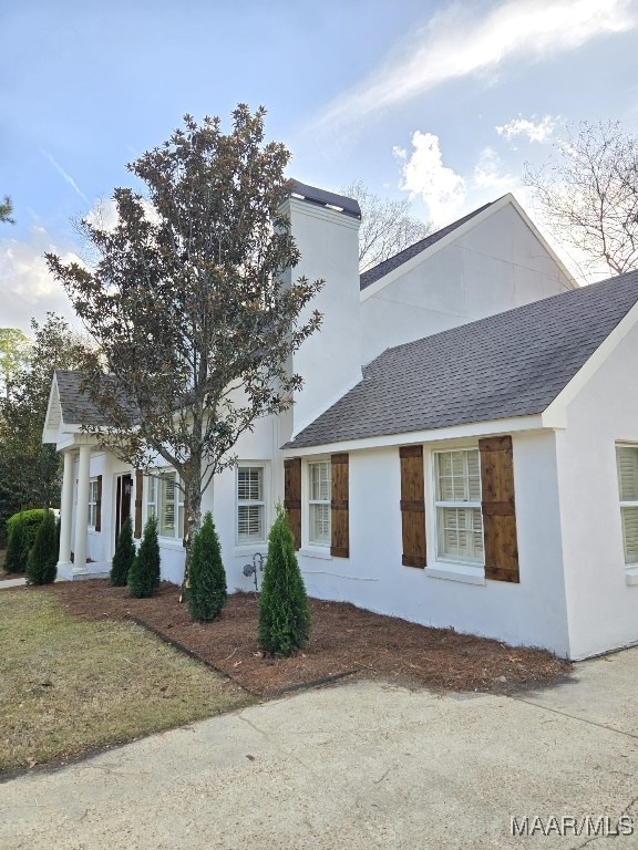 view of front facade with a shingled roof and stucco siding