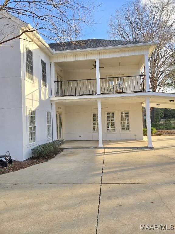 exterior space featuring a balcony, roof with shingles, and stucco siding