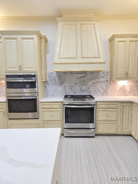 kitchen with backsplash, appliances with stainless steel finishes, cream cabinets, and light countertops