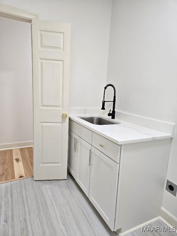 interior space with a sink, light wood-type flooring, a peninsula, and white cabinetry